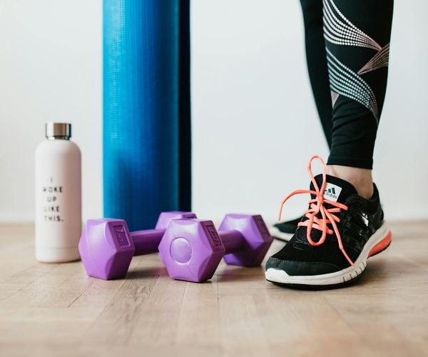 A collection of fitness tools like a notepad, water bottle, and yoga mat.