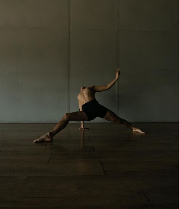Man performing a controlled core strength exercise in a minimalist dark setting.
